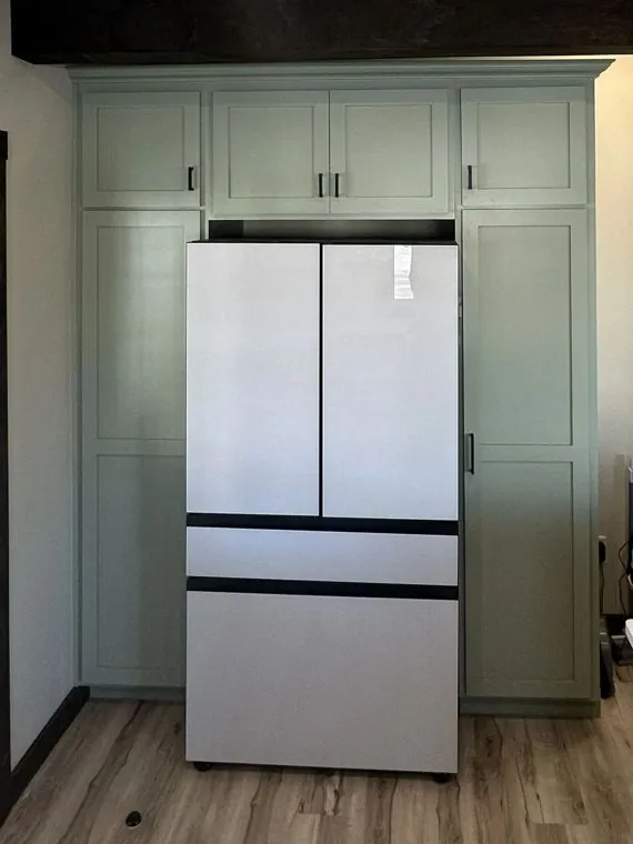 Full-height painted cabinetry framing the refrigerator — built by Amish Heritage Woodworks, Wisconsin