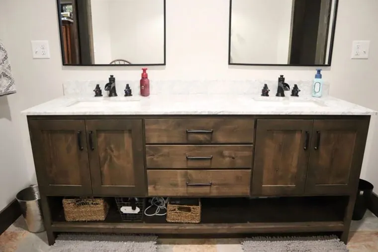 Double bathroom vanity in stained hardwood with open basket storage — built by Amish Heritage Woodworks, Wisconsin